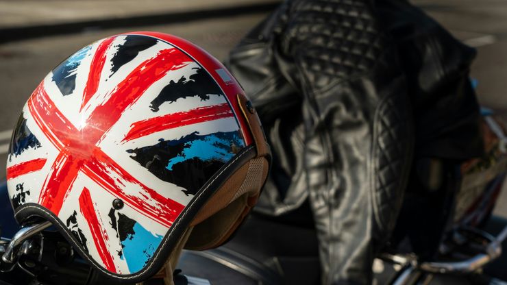 Union Jack covered bike helmet and motorcycle leathers on top of a motorcycle.