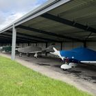 Light aircraft parked under cover in the open bay hangar at Thruxton Airfield
