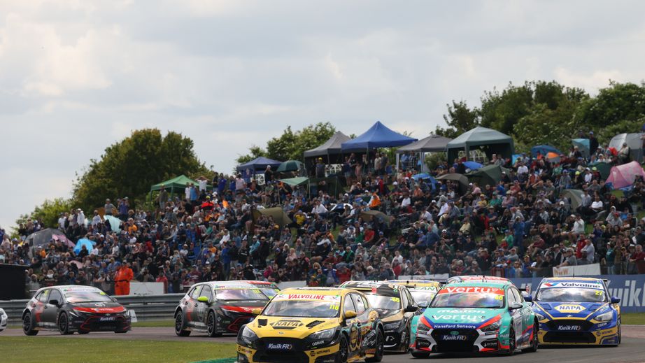 BTCC Cars racing at Thruxton with a full spectator bank in the background.