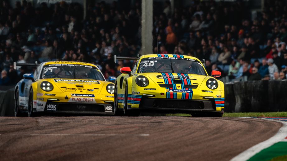 Porsche Carrera Cup GB racing at Thruxton. A full grandstand watching in the background.