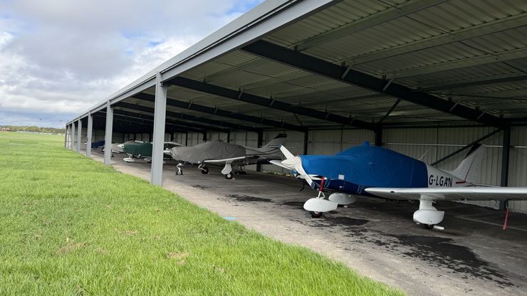 Light aircraft parked under cover in the open bay hangar at Thruxton Airfield