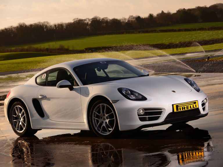 White Porsche Cayman on the skid pan with waterjets spraying in the background.